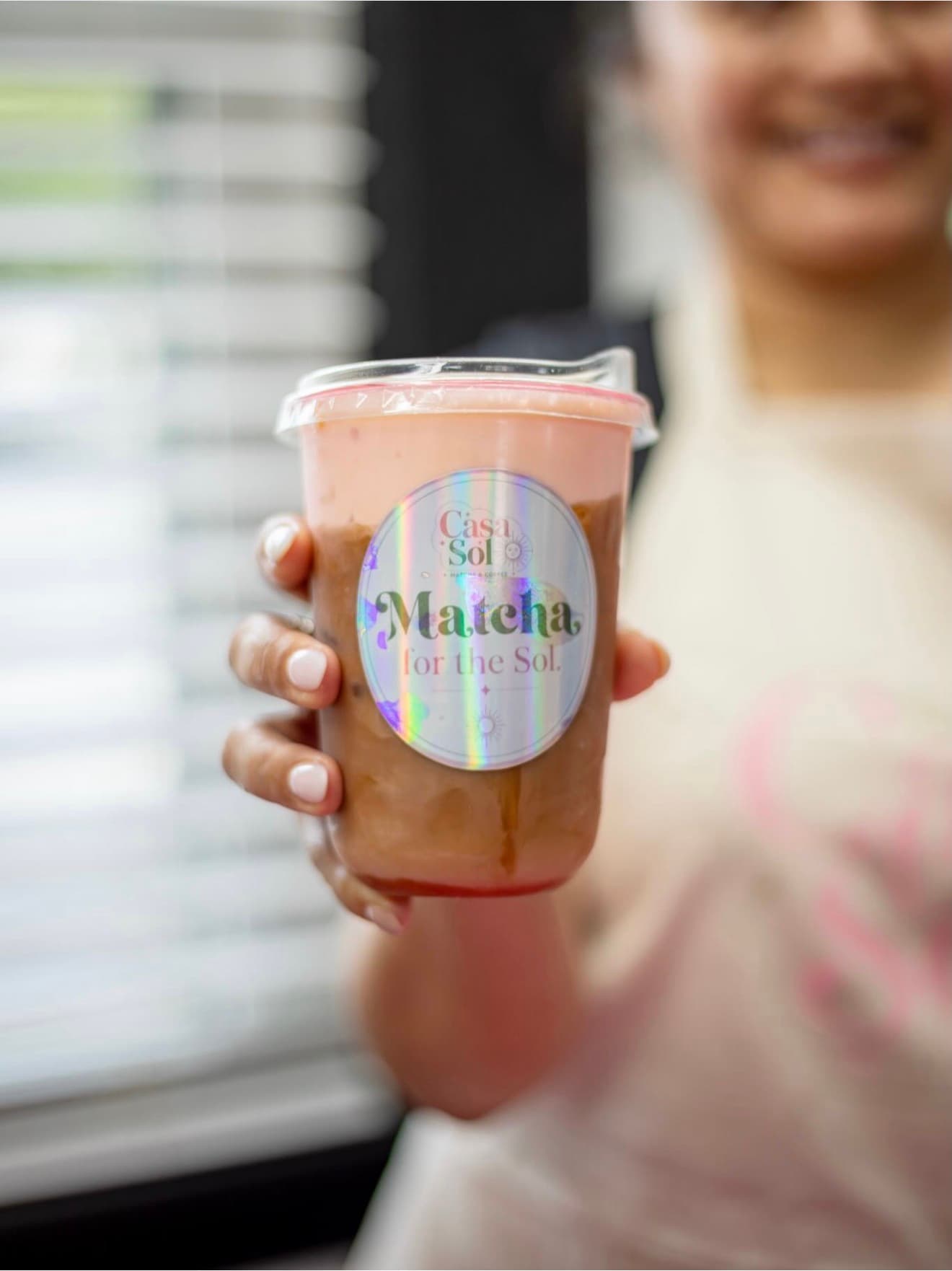 A smiling guest holding a freshly made Casa Sol matcha